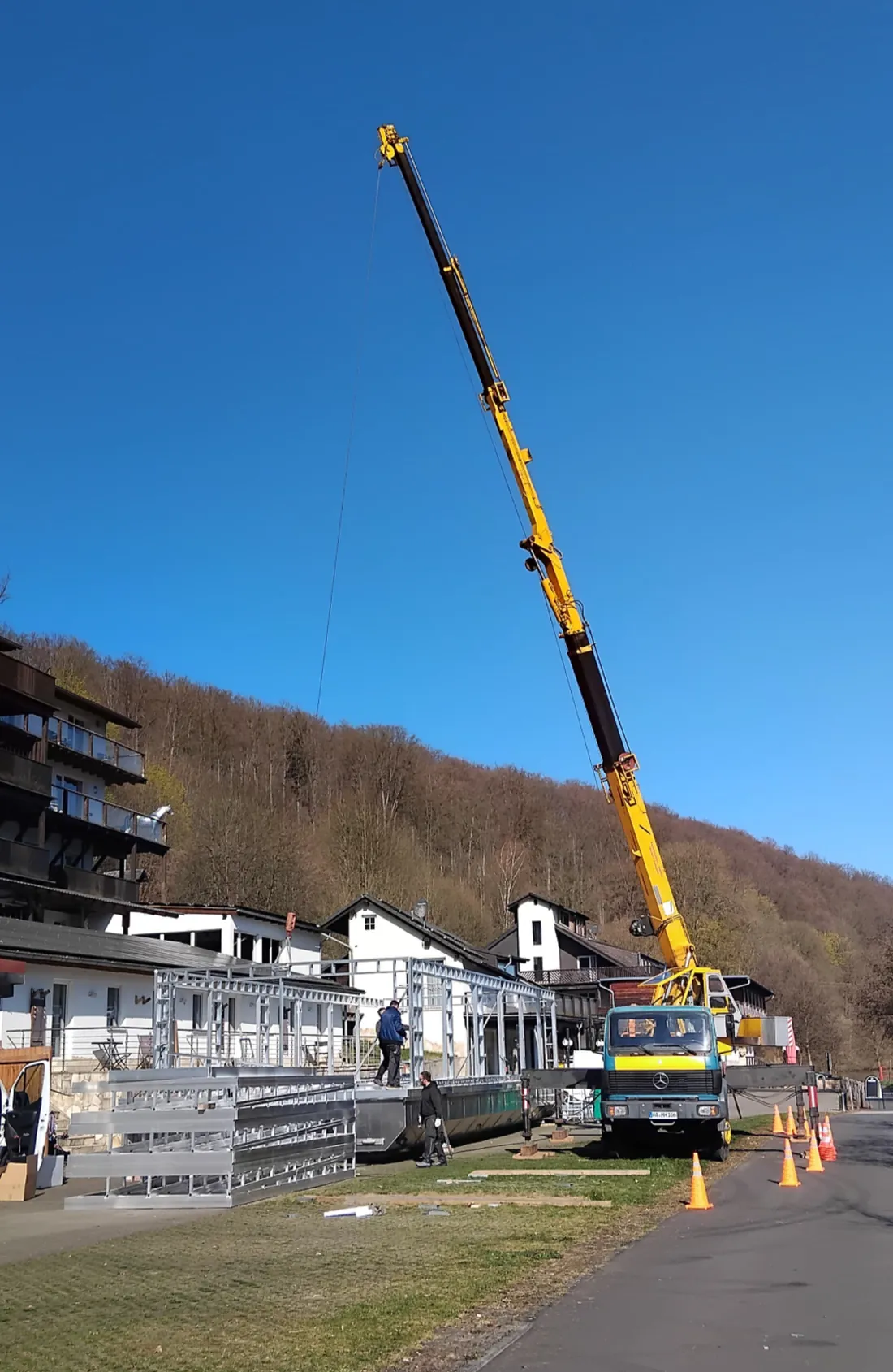Milanik Autokran arbeitet über ein Wohnhaus hinweg auf einem Hofgelände
